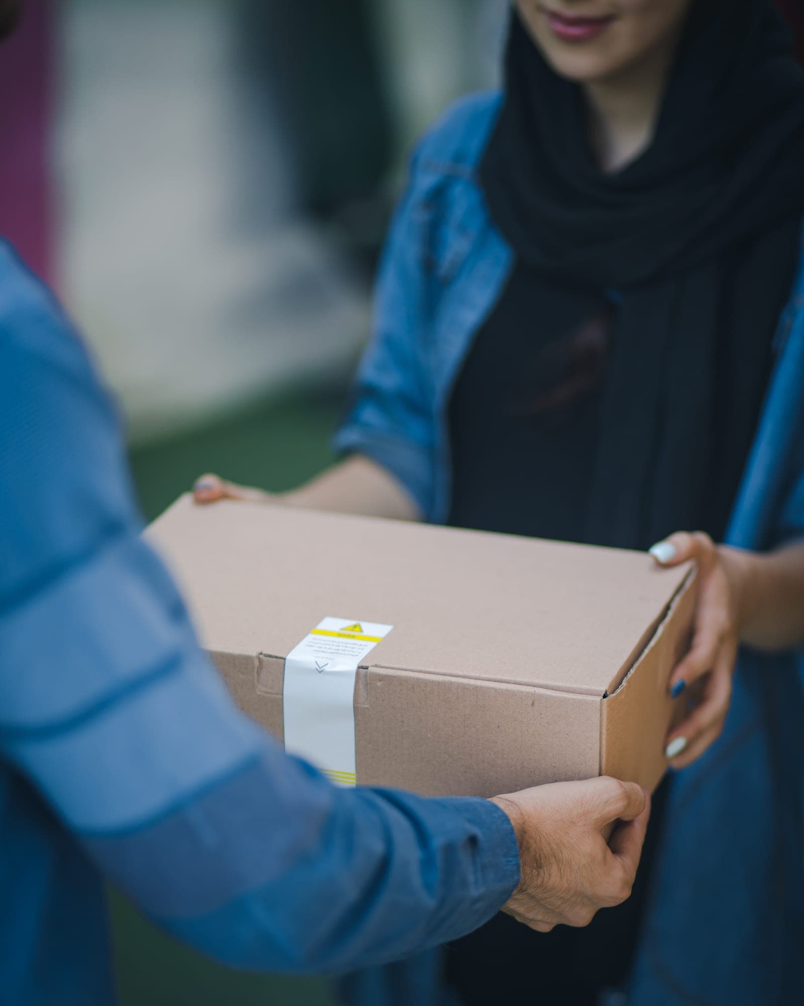One person handing a sealed cardboard box to another
